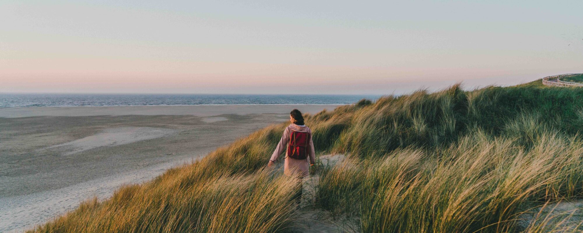 Vrouw loopt in de buurt van de zee bij zonsondergang